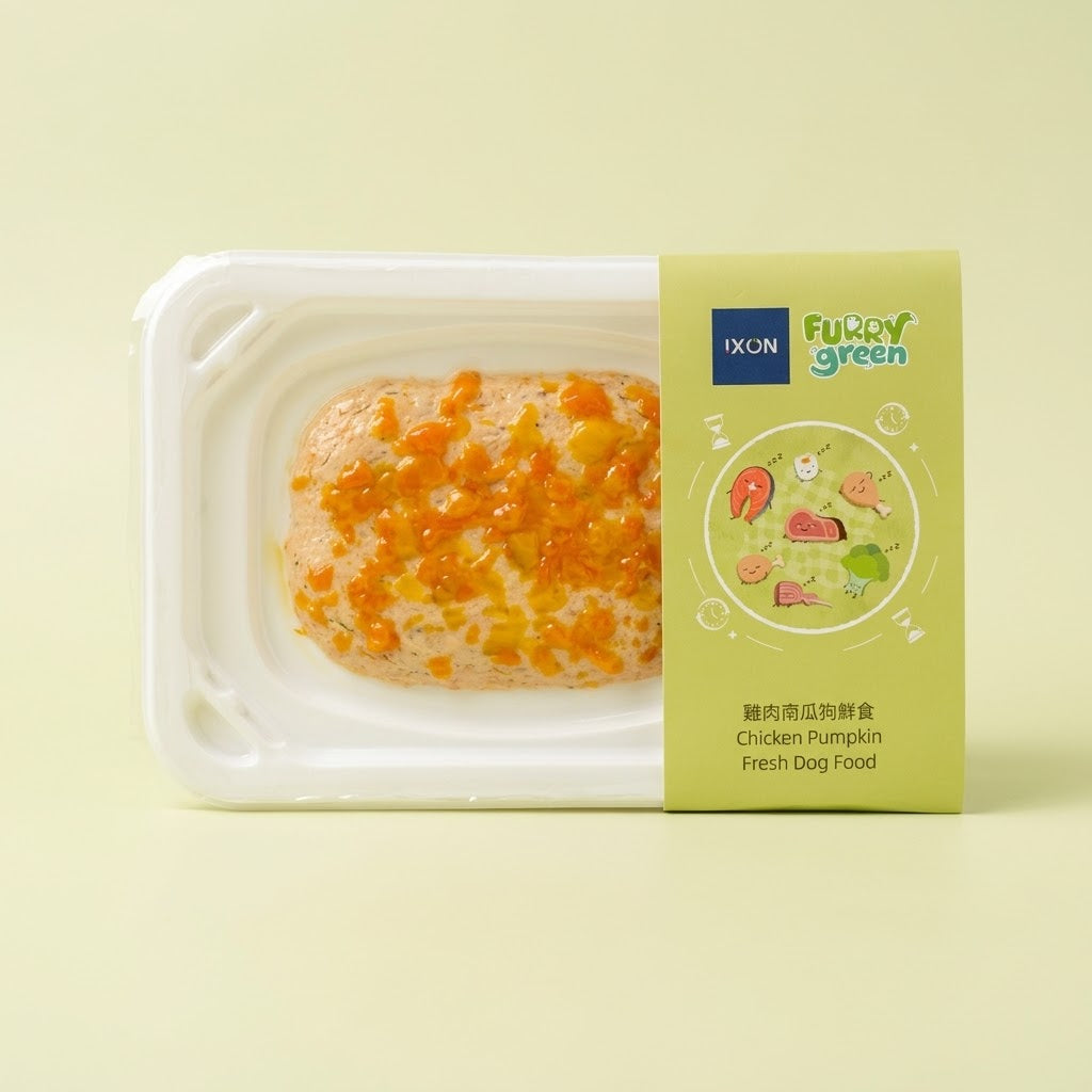 A packaged pet food product on a pale yellow background. The white plastic tray contains a rectangular piece of dog food topped with orange and yellow crumb pieces. Furry Green x Ixon